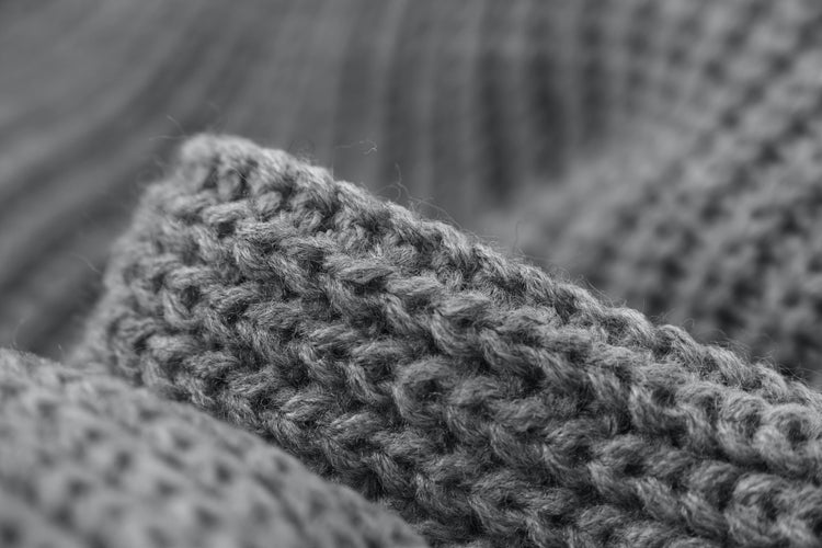 Close-up of textured gray knitted fabric with visible yarn fibers and stitches
