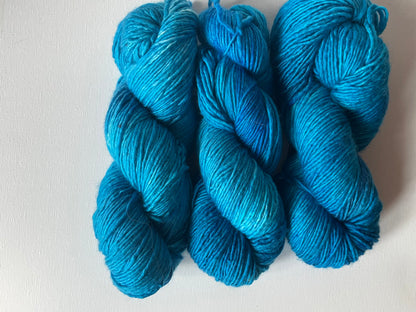 Three skeins of bright blue yarn on a white textured background