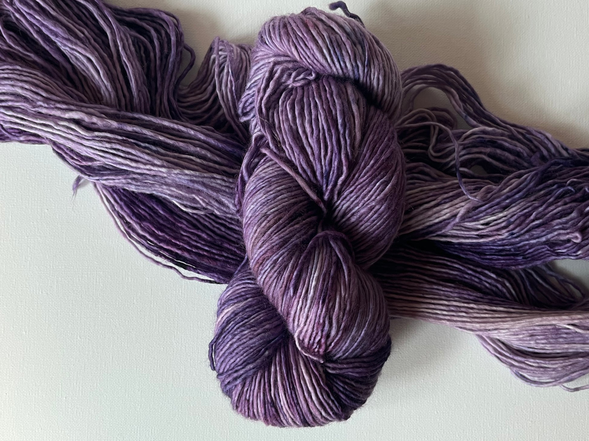 Close-up of a skein of variegated purple yarn on a white background