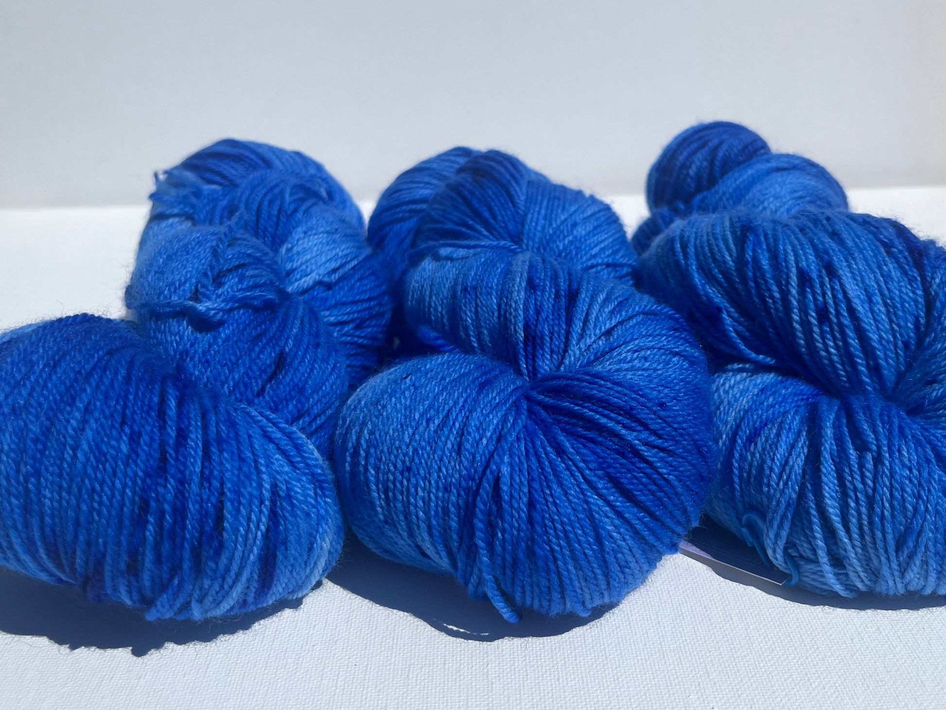 Close-up of several skeins of vibrant blue yarn on a white background