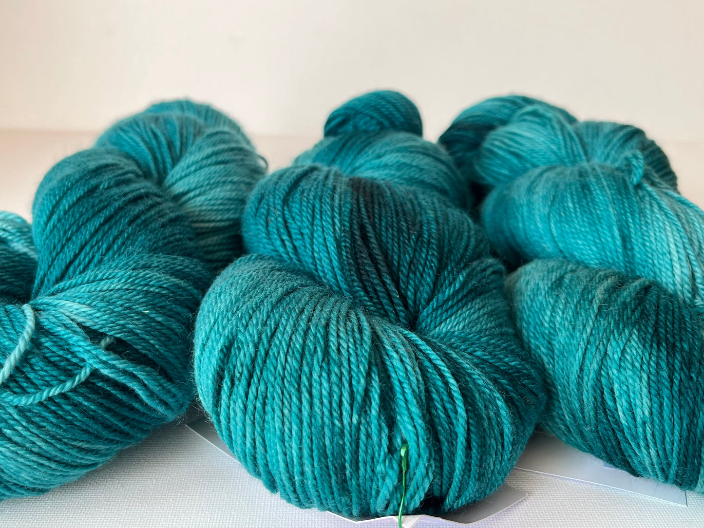 Close-up of teal blue wool yarn skeins on a white surface for knitting or crocheting