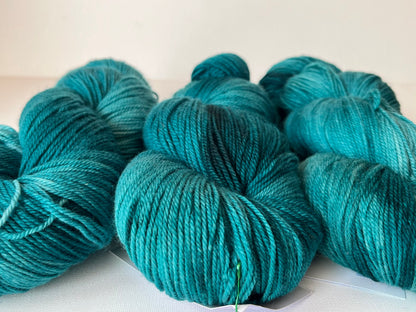 Close-up of teal blue wool yarn skeins on a white surface for knitting or crocheting