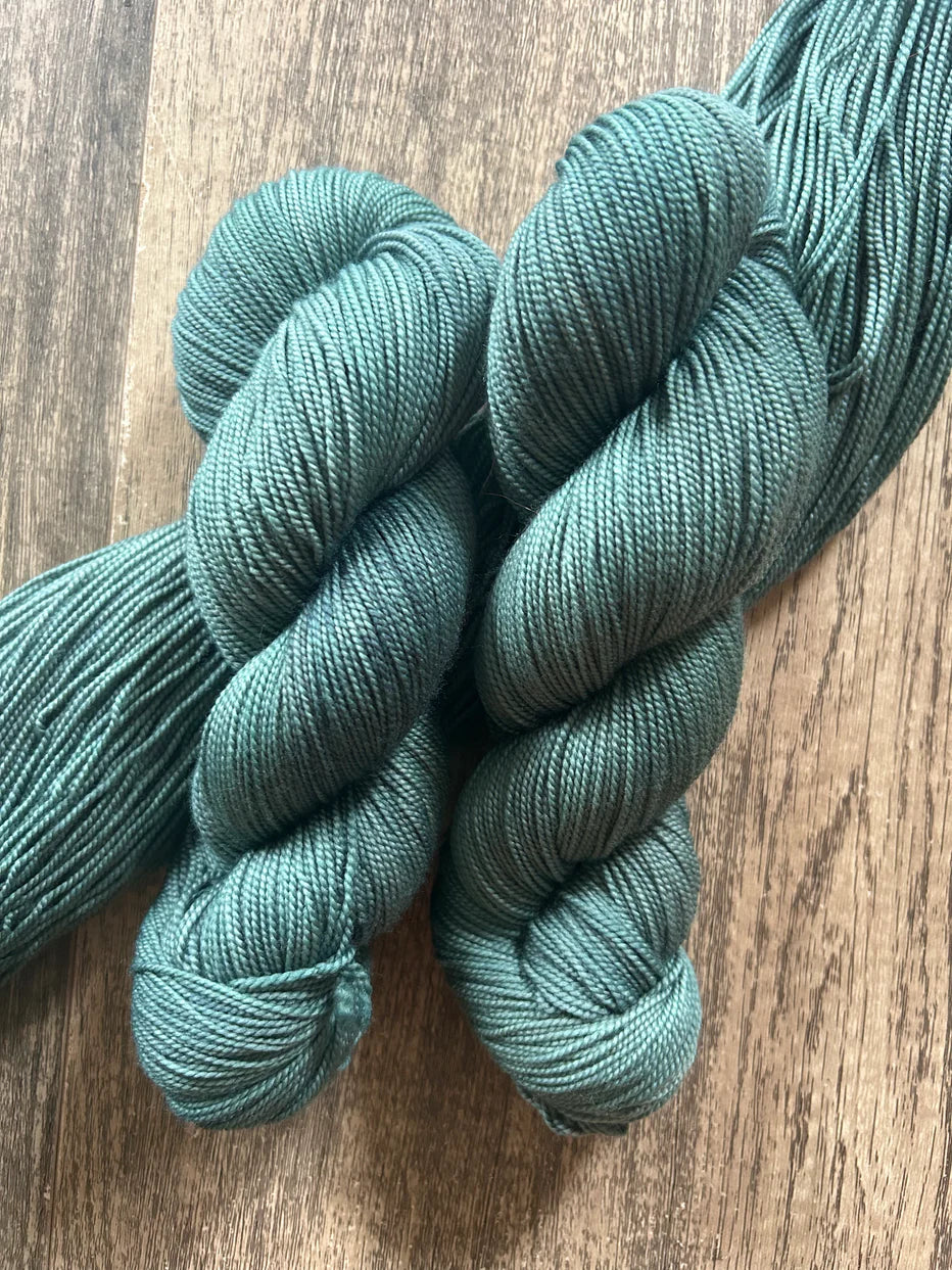 Two skeins of teal blue yarn on rustic wooden surface