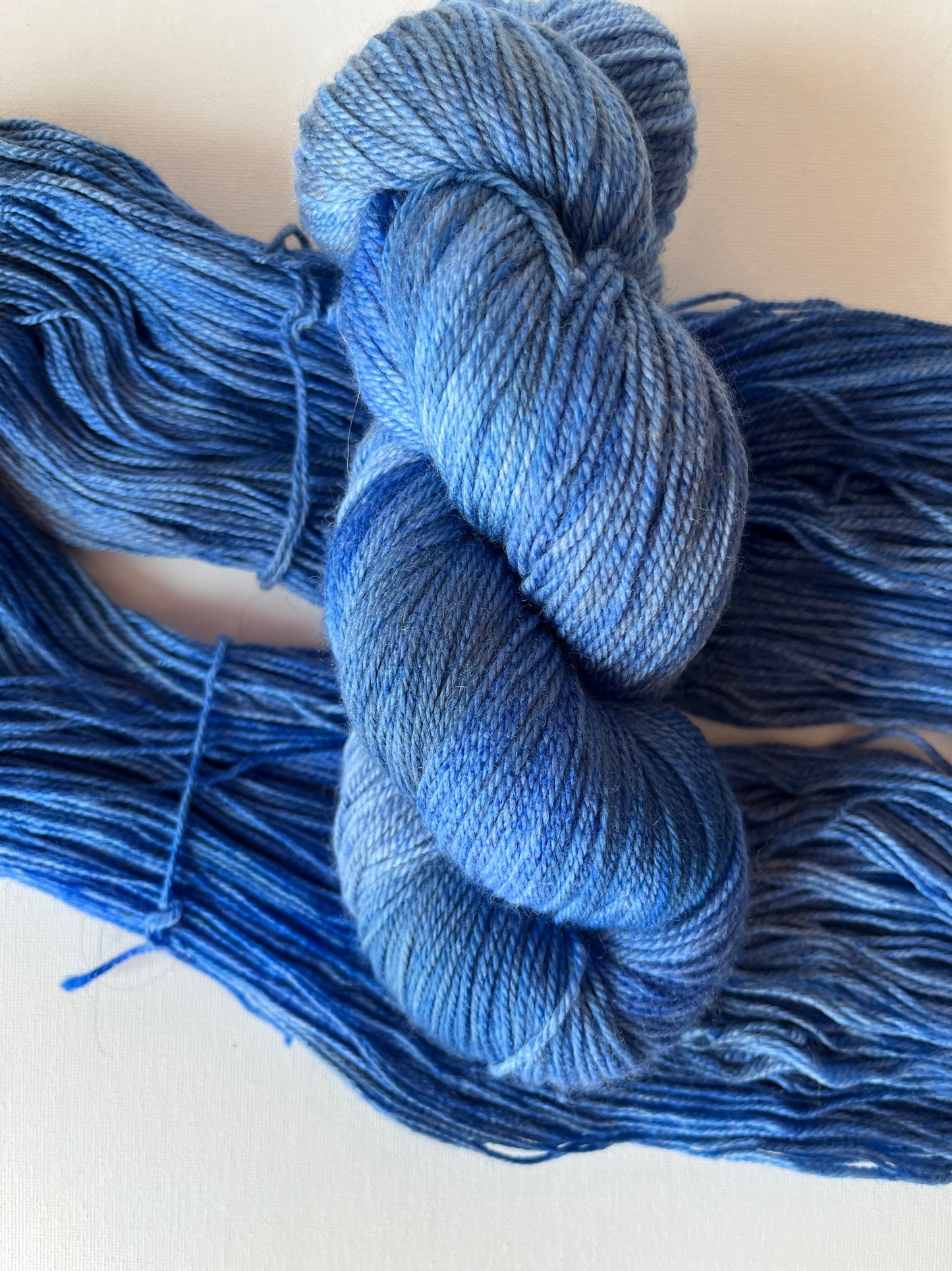 Hand-dyed blue yarn skein and strands on white background for knitting and crochet